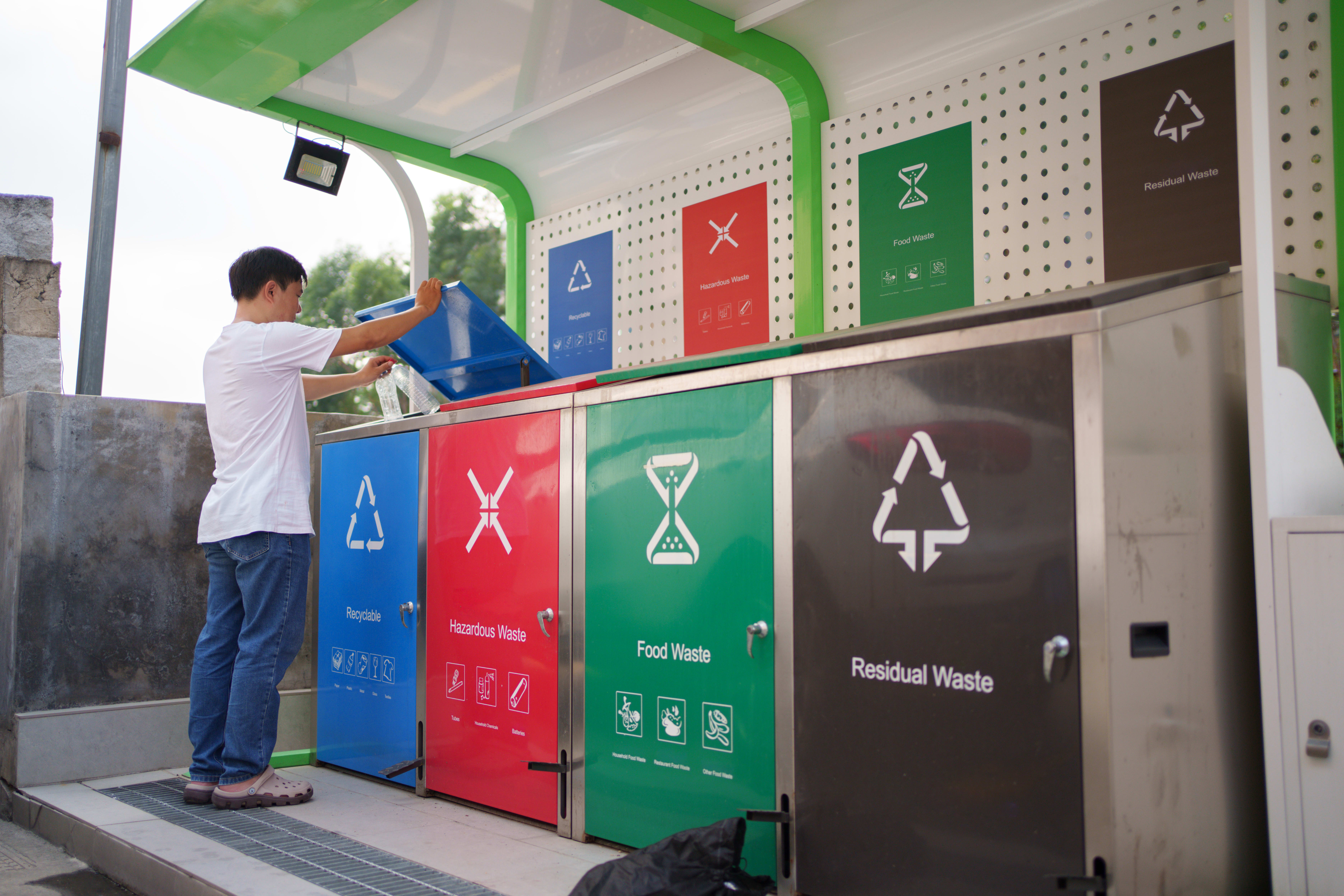 Image of man placing plastic bottle into recycling bin.